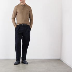 Model wearing Burberry clay brown cotton long-sleeve polo with check collar, styled with navy trousers and black loafers.