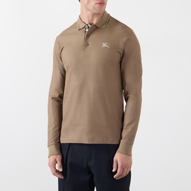 Model wearing Burberry clay brown long-sleeve cotton polo shirt with EKD embroidery and contrast collar buttons, styled with navy trousers