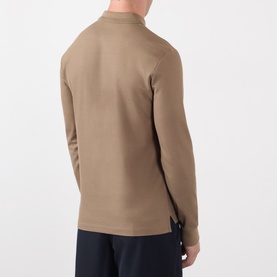 Model wearing Burberry clay brown long-sleeve cotton polo shirt, back view, paired with navy trousers.