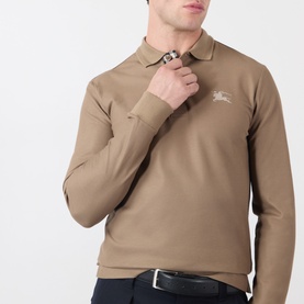 Model wearing Burberry clay brown long-sleeve cotton polo shirt with embroidered Equestrian Knight logo, paired with dark jeans and belt.
