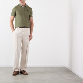 Model wearing Burberry olive cotton polo shirt with check collar trim, styled with stone wide-leg trousers and brown leather shoes
