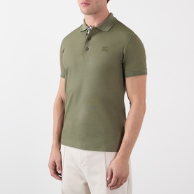 Model wearing Burberry olive cotton polo shirt with tonal embroidered logo, paired with white trousers.