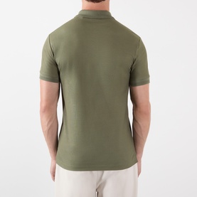Model wearing Burberry olive cotton polo shirt, rear view, styled with light beige trousers
