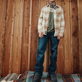 Model wearing Levi's Dark Hollow jeans styled with a plaid overshirt, green graphic tee and brown boots