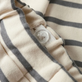 Lil Atelier baby trousers in Turtledove, close-up of cream and grey stripe fabric with snap button fastening detail