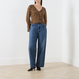 Model wearing Paige Hickory Multi silk blouse with floral print and long sleeves, styled with wide-leg blue jeans and black heels.