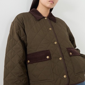 Model wearing Paige fern quilted jacket with contrast dark brown collar and patch pockets, gold snap buttons visible
