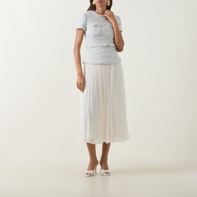 Model wearing Self-Portrait blue textured top and pleated midi skirt dress with white heeled mules