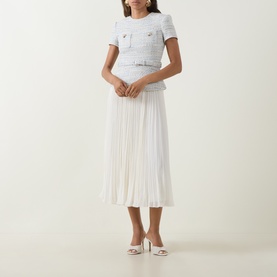 Model wearing Self-Portrait blue tweed-style top and white pleated midi skirt dress with white heeled mules