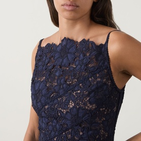 Model wearing Self-Portrait navy lace dress with scalloped neckline and thin shoulder straps, close-up detail shot.