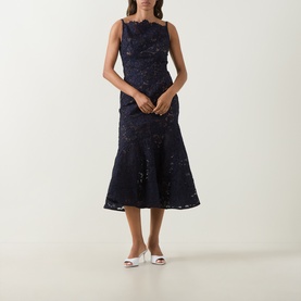 Model wearing Self-Portrait navy lace midi dress with fluted hem and scalloped neckline, styled with white heeled mules.