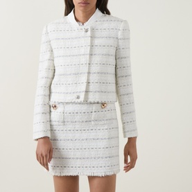 Model wearing Self-Portrait white cotton tweed jacket with stripe texture and jewel buttons, styled with matching mini skirt