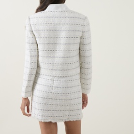 Model wearing Self-Portrait white cotton tweed-style jacket with horizontal stripe embellishment detail, shown from the back with matching mini skirt