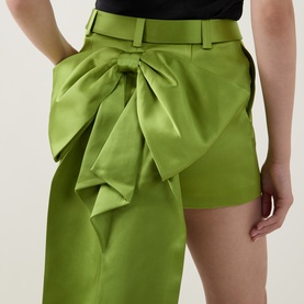 Model wearing Self-Portrait green satin mini skirt with oversized bow detail at the waist, tailored fit