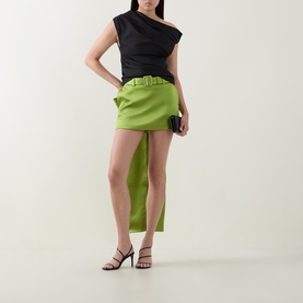 Model wearing Self-Portrait green asymmetric belted mini skirt, styled with black one-shoulder top and black strappy heels