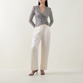 Model wearing Self-Portrait grey ruched wrap-style long-sleeve top with cream wide-leg trousers and black strappy heels.