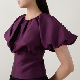 Model wearing Self-Portrait purple top with dramatic puffed short sleeves and gathered neckline detail.