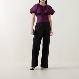 Model wearing Self-Portrait purple structured puff-sleeve top with black wide-leg trousers and strappy heels.