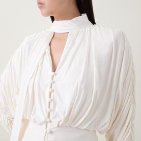 Model wearing Self-Portrait cream draped top with choker neckline, button-front detail, and voluminous sleeves in viscose blend.