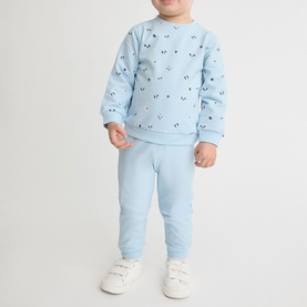 Model wearing Street Monkey light blue 2-piece baby set with all-over print sweatshirt and joggers, styled with white trainers