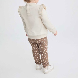 Model wearing Street Monkey Ecru 2 Piece set, back view showing frill sweatshirt and brown floral joggers, baby months sizing