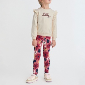 Model wearing Street Monkey ecru frill sweatshirt and floral pink leggings set, styled with white trainers