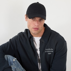 Model with Acne Back Logo Baseball Cap in black, six-panel curved brim design, worn with black Acne Studios jacket and white tee