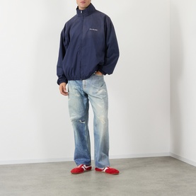 Model wearing Acne navy casual jacket with light wash distressed jeans and red trainers
