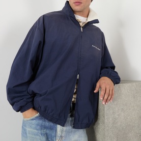 Model wearing Acne navy casual jacket with zip fastening and stand collar, styled with checked shirt and light wash jeans