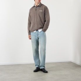 Model wearing Acne Logo Knitted Polo Sweater in brown melange, styled with light blue straight-leg jeans and black loafers.