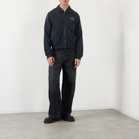 Model wearing Acne faded black cotton zip-up sweatshirt with collar, styled with black wide-leg jeans and black loafers
