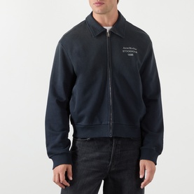 Model wearing Acne faded black zip-up sweatshirt with collar, chest logo detail, paired with dark jeans