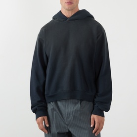 Model wearing Acne black cotton hoodie sweatshirt, styled with grey striped trousers