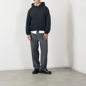Model wearing Acne black cotton hoodie sweatshirt, styled with white shirt underneath and grey trousers