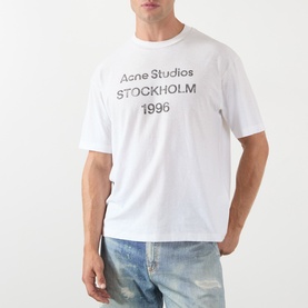 Model wearing Acne 1996 Logo T-Shirt in dusty white with distressed stamp logo, styled with light wash jeans