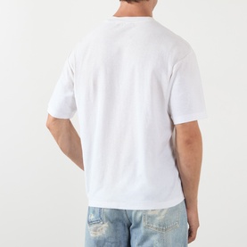 Model wearing Acne 1996 Logo T-Shirt in dusty white, rear view, crew neck, dropped shoulders, styled with light-wash jeans.