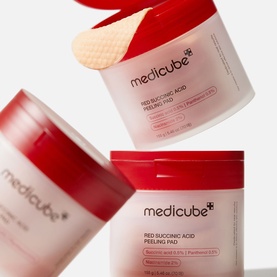 Medicube Red Succinic Acid Peeling Pads in two stacked tubs with one textured cotton pad shown on top