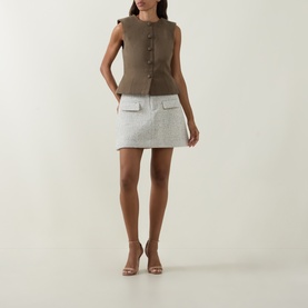 Model wearing Odd Muse grey wool mini skirt with patch pockets, styled with a brown sleeveless top and nude heeled sandals.