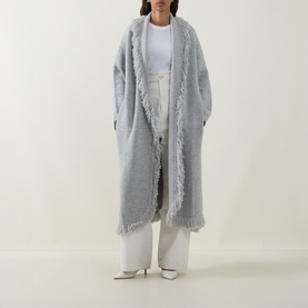 Model wearing Odd Muse grey wool longline fringe-trim open coat, styled with white wide-leg trousers and white pointed heels.