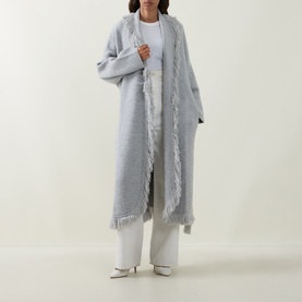 Model wearing Odd Muse grey wool longline cardigan coat with fringe trim edges, styled with white wide-leg trousers and white heels.