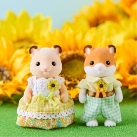 Two Sylvanian Families hamster figures in yellow and green sunflower outfits, posed against a bright sunflower backdrop