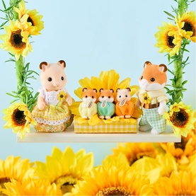 Calico Critters hamster family figures in sunflower-themed outfits, displayed on a shelf surrounded by yellow sunflower decorations