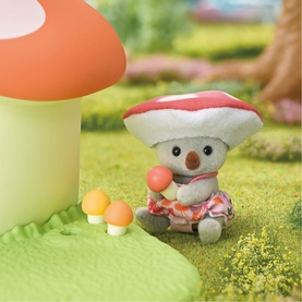 Sylvanian Families small mouse figure wearing red mushroom cap hat, seated on grass beside miniature mushrooms and large toadstool prop