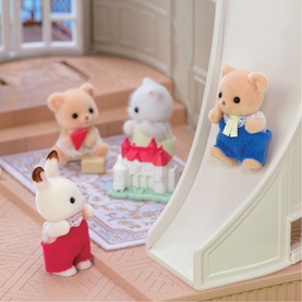 Sylvanian Families figures playing in a dollhouse interior, including bear and rabbit characters on a slide and rug