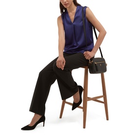 Model wearing Hobbs violet blue sleeveless satin V-neck top with wide-leg black trousers and black heels, carrying a small dark crossbody bag