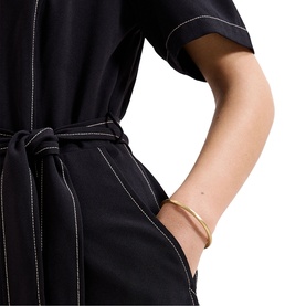 Model wearing Phase Eight black dress with white contrast stitching and self-tie belt, styled with a gold cuff bracelet