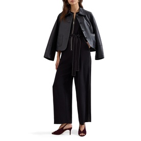 Model wearing Phase Eight black wide-leg jumpsuit with contrast stitching, styled with black leather zip jacket and burgundy heeled mules