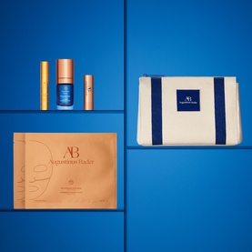 Augustinus Bader skincare set with serum, lip treatment, face mask sachet, and cream pouch in navy and ivory