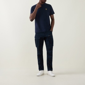 Model wearing Belstaff Phoenix Logo T-Shirt in Dark Ink, crew neck, with navy cargo trousers and white trainers.