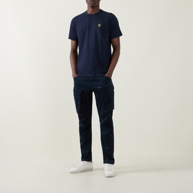 Model wearing Belstaff Phoenix Logo T-Shirt in Dark Ink, crew neck, chest logo detail, styled with matching navy cargo trousers and white trainers.